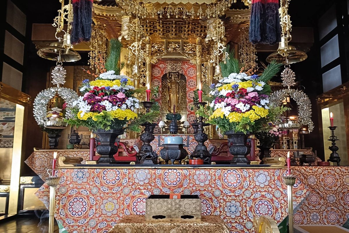広済寺の本堂の内陣。中央に阿弥陀如来の立像、両脇に花が供えられている