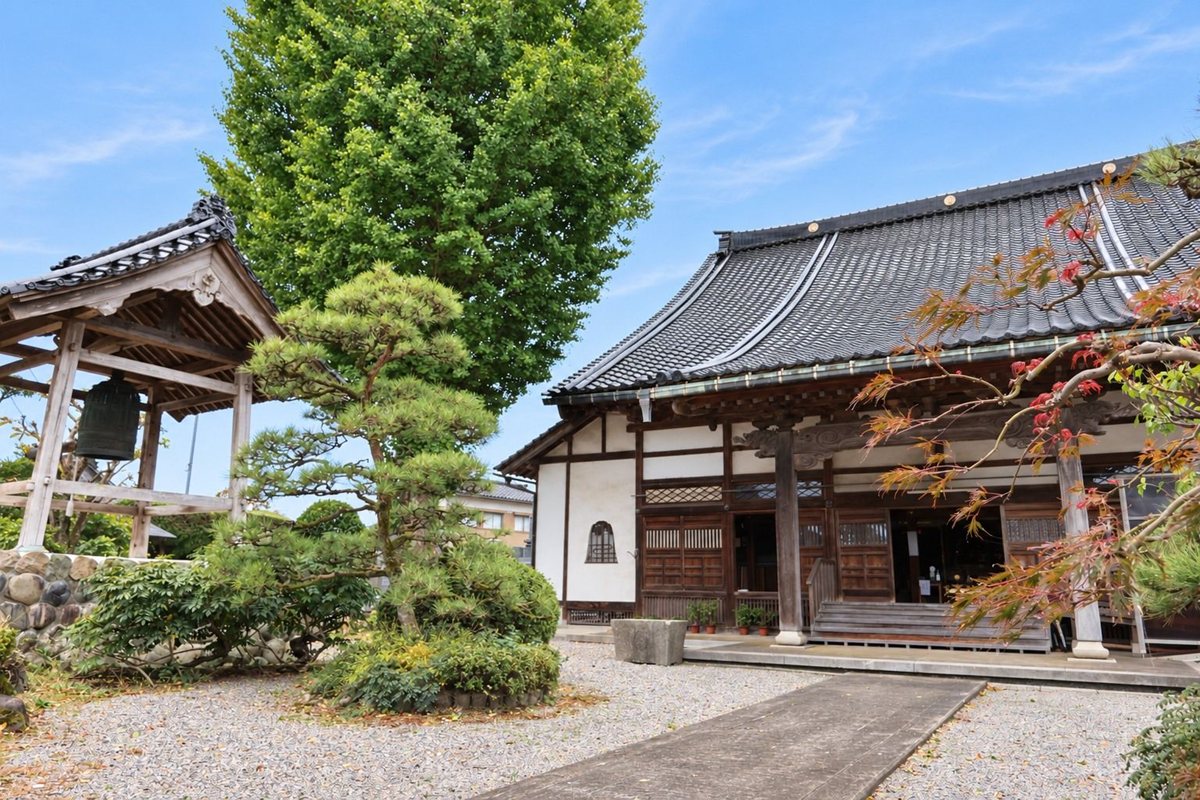 広済寺の境内。右に本堂、左に鐘楼、そのあいだに大きな銀杏と松の木が立っている